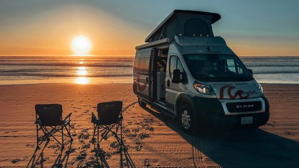 roadsurfer camper van with a raised roof parked on a beach.