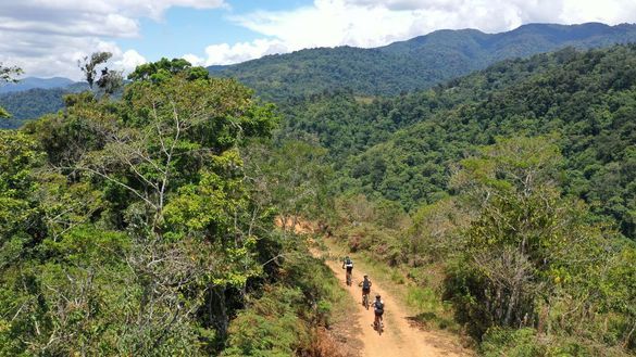 Travellers on e-bikes ride dirt path winding through a lush, green forest in Costa Rica Travellers on e-bikes ride dirt path winding through a lush, green forest in Costa Rica
