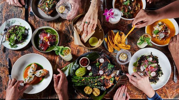 People share a tableful of food at Little Bull, a fine-dining experience in Pocho cuisine. Serving an evolving menu of taste fusions; honoring America's ever-changing influences and locally available ingredients.