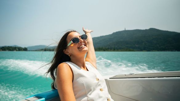 Summer in Austria: A woman in the back of a boat on a lake. 